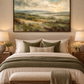 Green landscape wall art above a bed in a warm neutral bedroom
